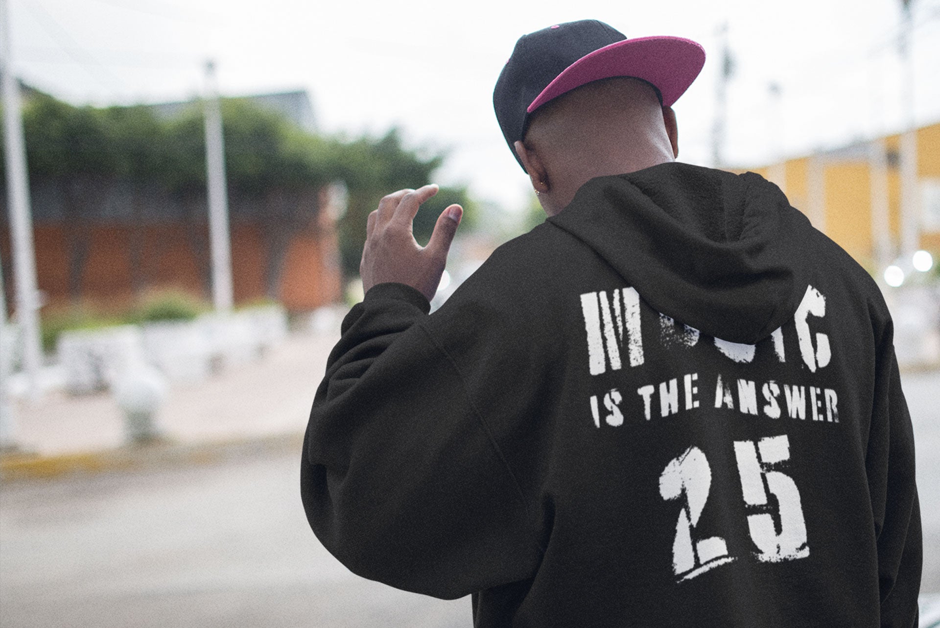 A young man wearing a Music Is The Answer 25th Anniversary hoodie 